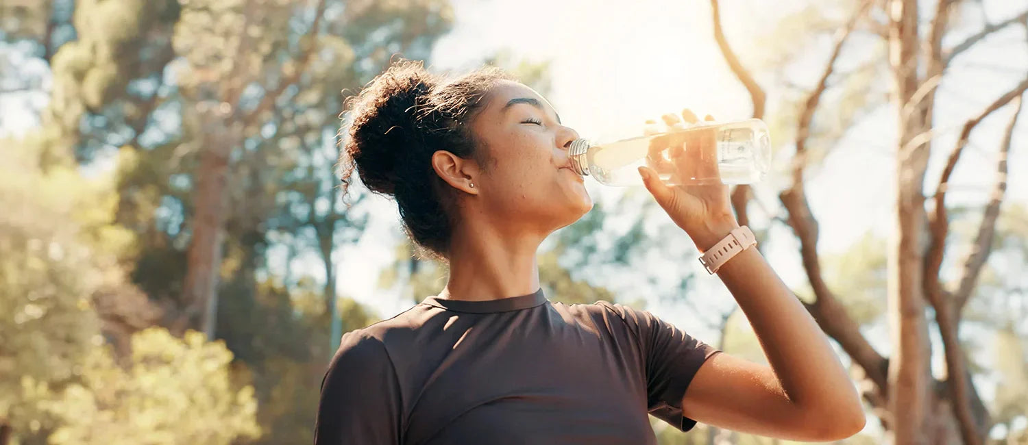 Woman drinking water outdoors to support gut health and daily digestive wellness